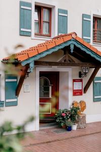une porte d'entrée d'un bâtiment avec un toit rouge dans l'établissement Hotel Vogtareuther-Hof, à Vogtareuth