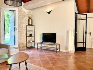 a living room with a television on a tiled floor at Le Clos Gallien - Maison coucoute in Illats