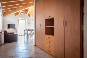 a kitchen with wooden cabinets and a living room at Appartamento alla Brisa Grauno Ospitar in Grauno