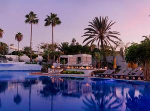 a swimming pool with palm trees and a resort at H10 Gran Tinerfe - Adults Only in Adeje