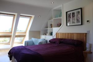 a bedroom with a bed and a chair and two windows at Cherry Trees in Stowmarket