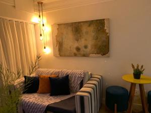 een woonkamer met een bank en een schilderij aan de muur bij Maravilhoso apartamento 2 quartos vista mar no Ondina Apart in Salvador