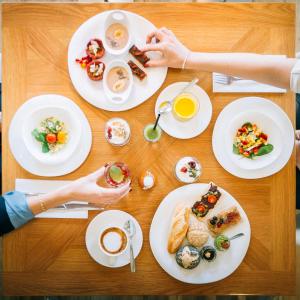 a table with plates of food and a person holding a cup of coffee at Petit Palace Boqueria Garden in Barcelona