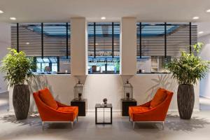 a lobby with two chairs and a table and windows at Wyndham Stuttgart Airport Messe in Stuttgart