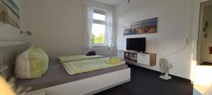 Dieses weiße Zimmer verfügt über ein Bett und einen TV. in der Unterkunft Ferienwohnungen "PureFitness" am Elberadweg in Tangermünde in Tangermünde