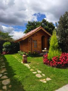 a small wooden cabin in a yard with flowers at Cabañas Villa Isabel in Cajicá