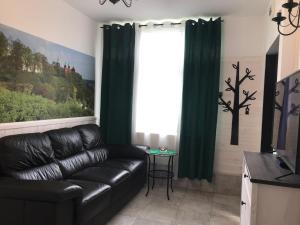 a living room with a black leather couch and a window at Płock by day in Płock