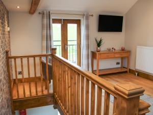 a wooden staircase in a house with a television at Meadow Barn in Craven Arms