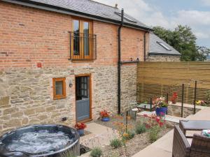 a brick house with a hot tub in front of it at Meadow Barn in Craven Arms