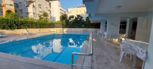 a large swimming pool with white chairs and a building at Tunali Apart Hotel in Antalya