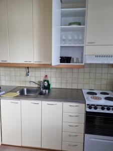 uma cozinha com armários brancos, um lavatório e um fogão em Studio at Koulukatu em Savonlinna