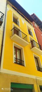 un edificio amarillo con balcones en un lateral en Txoko 48, en Pamplona