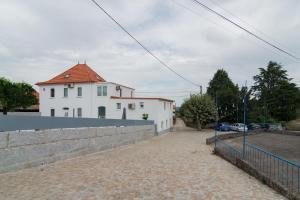 ein weißes Gebäude mit rotem Dach neben einer Wand in der Unterkunft Casas Madalena in Seia