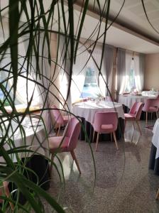 a restaurant with tables and pink chairs and plants at Ristorante Locanda Dussin in Oderzo