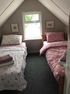een slaapkamer op zolder met 2 bedden en een raam bij Rose Cottage: Delightful 4 bedroom detached home in Portrush