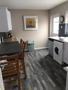 a kitchen with a washing machine and a table and chairs at Rose Cottage: Delightful 4 bedroom detached home in Portrush