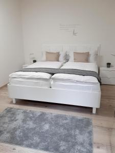 フォグツブルクにあるFerienwohnung "Am Blauwasser" mit Infrarotkabineのラグ付きの客室内の大きな白いベッド