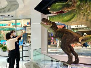 a woman standing next to a dinosaur in a store at Henn na Hotel Seoul Myeongdong in Seoul