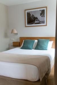 una camera da letto con un grande letto bianco con cuscini blu di Les Voyageurs a Saint-Renan
