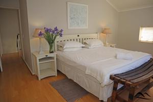 um quarto com uma cama com um vaso de flores em The Dunes 112 em Plettenberg Bay