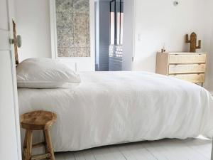 Dormitorio blanco con cama blanca y taburete de madera en Gîte Senlisse, 4 pièces, 6 personnes - FR-1-527-11, en Senlisse