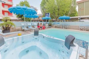 uma piscina num hotel com guarda-sóis azuis em Hotel Bagli em Rimini