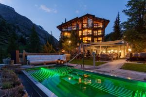 uma casa com piscina em frente a um edifício em Suitenhotel Zurbriggen em Zermatt