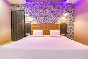 a bedroom with a large white bed with purple lights at FabHotel Rudra Inn & Cafe in Gorakhpur