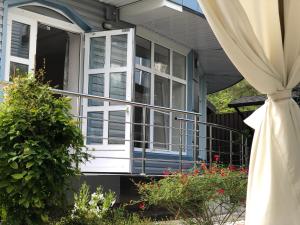 オリギンカにあるFlora&Komfortの白窓とカーテン付きのポーチのある家