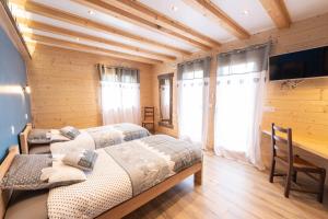 LE CHALET BAZAN في آرفيو: سريرين في غرفة بجدران خشبية ونوافذ
