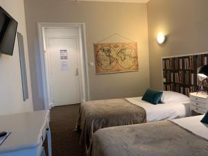 a hotel room with two beds and a book shelf at Hôtel Trianon Tours in Tours