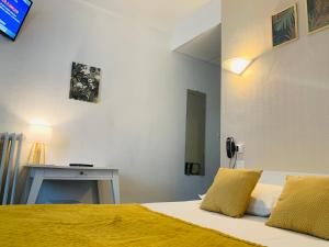 トゥールにあるオテル トリアノン トゥールのベッドルーム1室(黄色いシーツとテーブル付きのベッド1台付)