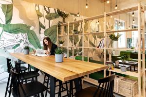 a woman sitting at a table in a room with plants at B&B HOTEL Basel in Basel