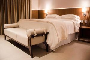 uma cama grande num quarto de hotel com uma cadeira em Amazon Taiamã Hotel em Cuiabá
