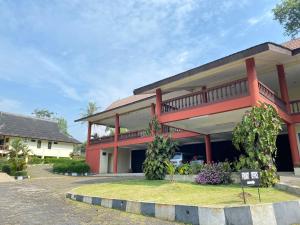 una casa roja con balcón frente a ella en SUPER OYO Flagship 90644 Cottage Nalendra Nuansa Nusantara, en Subang