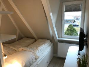 ein kleines Bett in einem Zimmer mit Fenster in der Unterkunft Silwai OG in Westerland