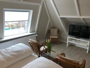Zimmer mit einem Bett, einem TV und Stühlen in der Unterkunft Silwai OG in Westerland