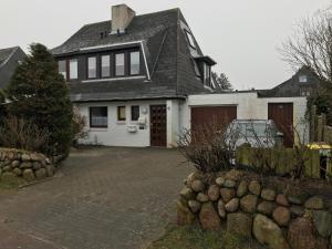 ein weißes Haus mit einem Tor und einer Einfahrt in der Unterkunft Silwai OG in Westerland