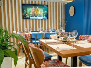 Brosko Hotel Arbat في موسكو: مطعم به طاولات وكراسي وتلفزيون على الحائط