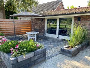 a patio with an umbrella and a table and flowers at Rustig Tiny House in het groen nabij Enschede & UT in Enschede +20 photos