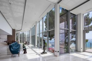 a lobby with a blue chair and large windows at Royal Neptun Hotel in Dubrovnik