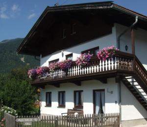 une maison blanche avec des fleurs sur un balcon dans l'établissement Grafn-Hof, à Schleching