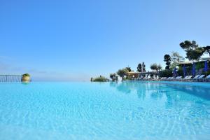 a large swimming pool with blue water and chairs at Hotel Caesar Augustus in Anacapri