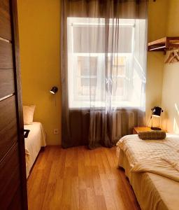 een slaapkamer met een raam, een bed en een houten vloer bij Kohtu Apartment Epoch in Kuressaare