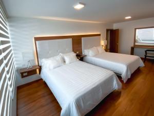 two beds in a hotel room with white sheets at Hotel Miraflores in Ambato