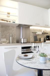 een witte keuken met een tafel en twee wijnglazen bij Elégant appartement moderne - Cure et vacances in Balaruc-les-Bains