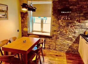 une salle à manger avec une table en bois et un mur en pierre dans l'établissement Kohtu Apartment Epoch, à Kuressaare