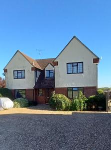 a large white house with black windows at Barn Farm Guest House in Cold Norton