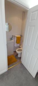 a bathroom with a toilet and a yellow towel at Barn Farm Guest House in Cold Norton