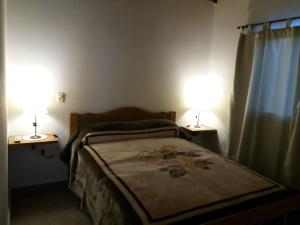 een slaapkamer met een bed en twee lampen op twee tafels bij Deptos del sur in Tandil